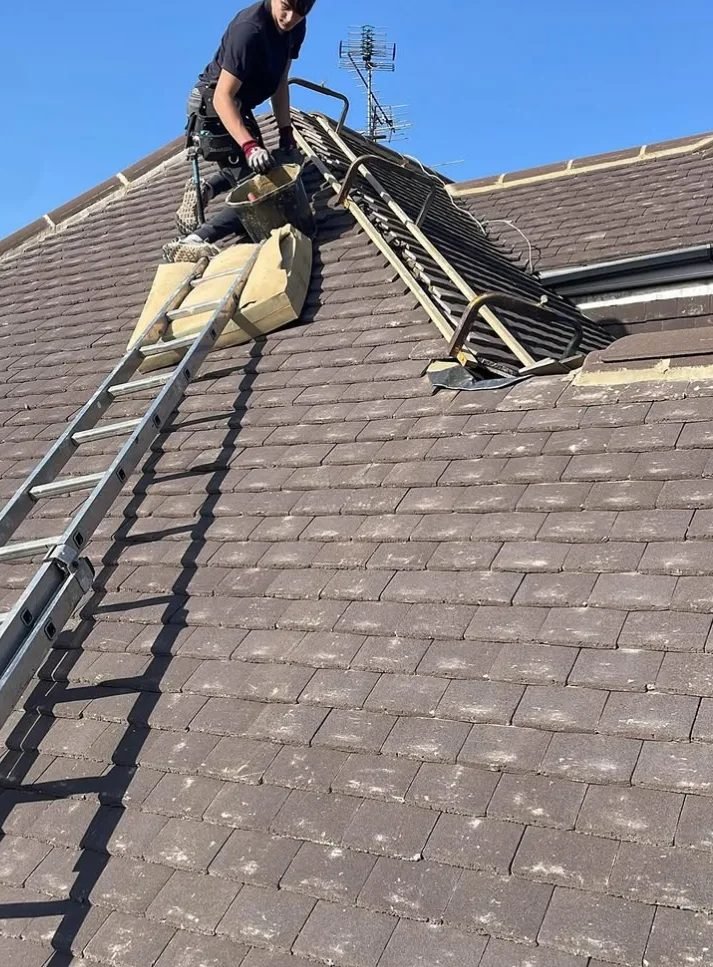 Roofer working at the ridge of a tiled roof
